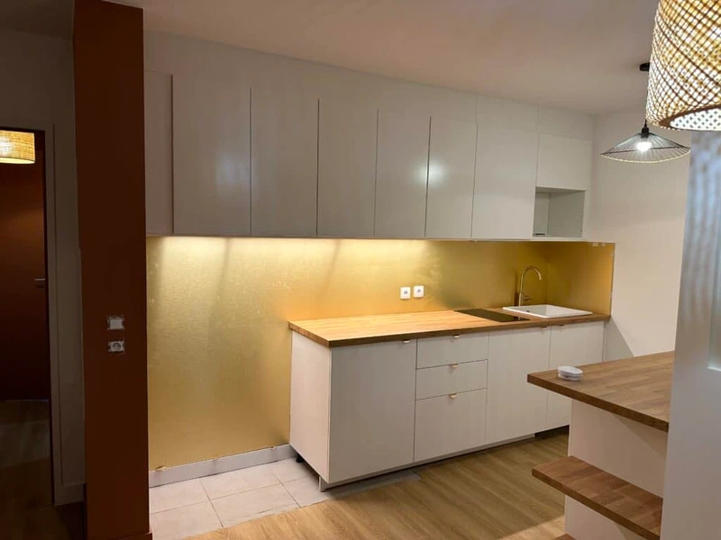 Cuisine contemporaine aux façades blanches, plan de travail en bois et crédence ocre