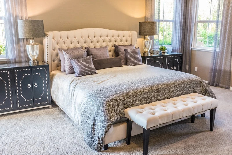 Aménagement intérieur d’une chambre élégante avec lit capitonné et mobilier coordonné