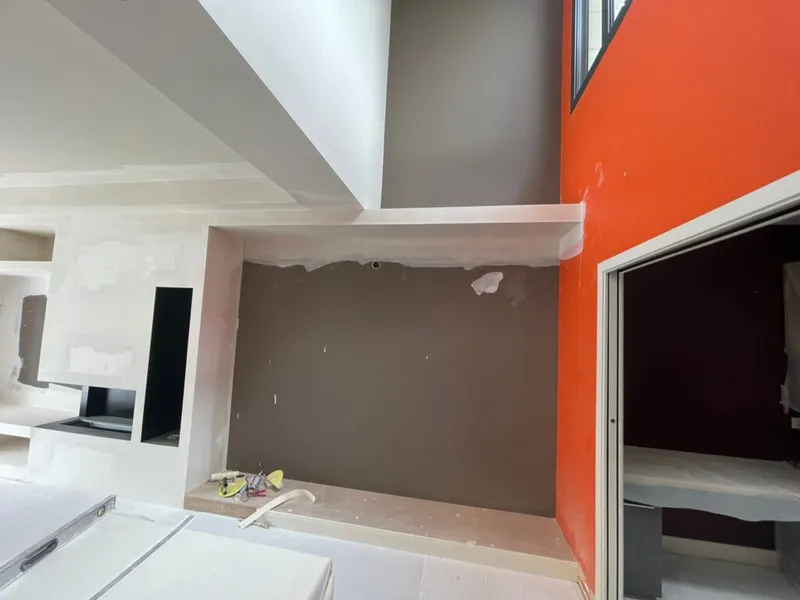 Bibliothèque et cheminée en cours de réalisation avec enduits, outils et protections de chantier