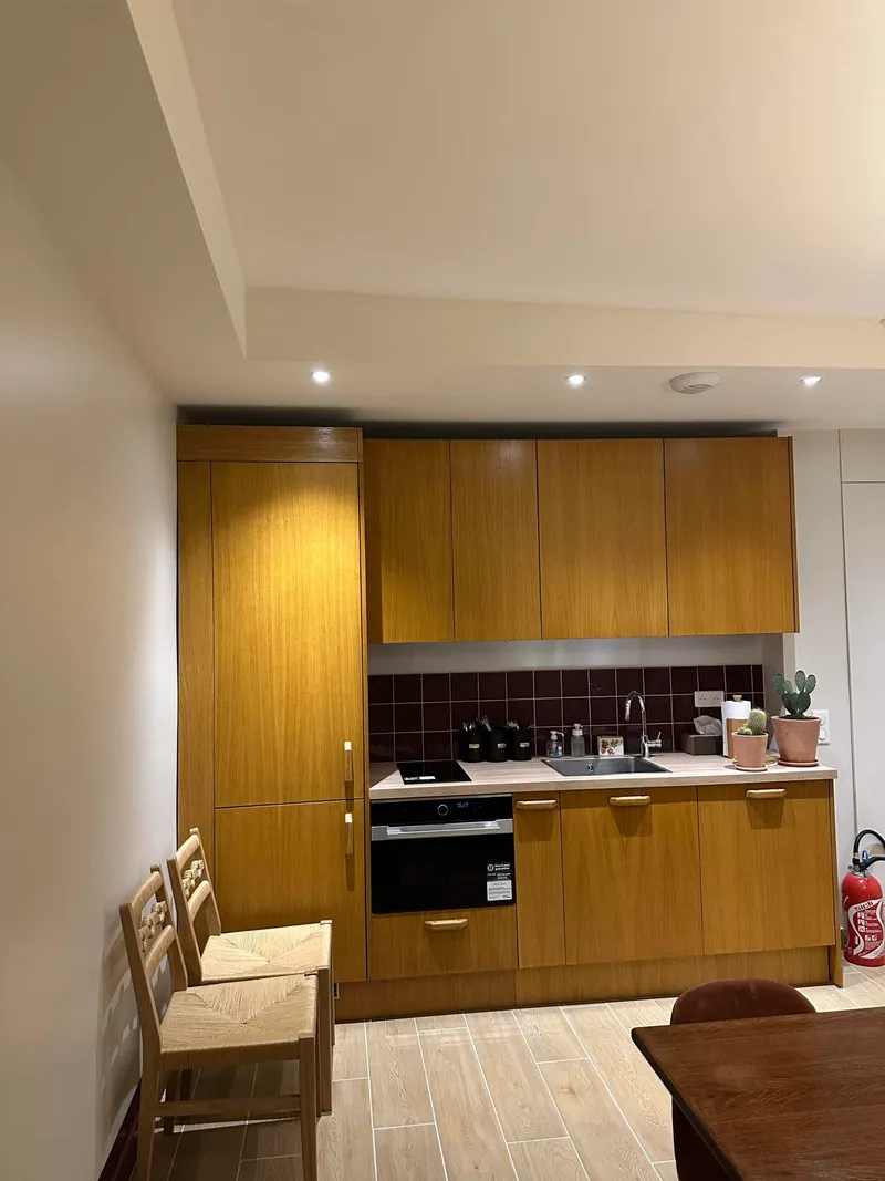 Cuisine avec façades en bois, four encastré et crédence sombre