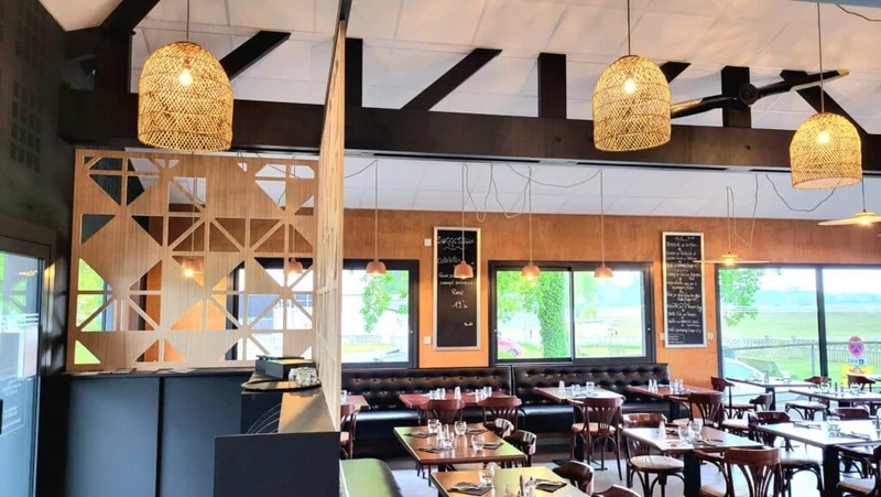 Restaurant contemporain avec banquettes, tables dressées, claustra en bois et suspensions en fibres naturelles