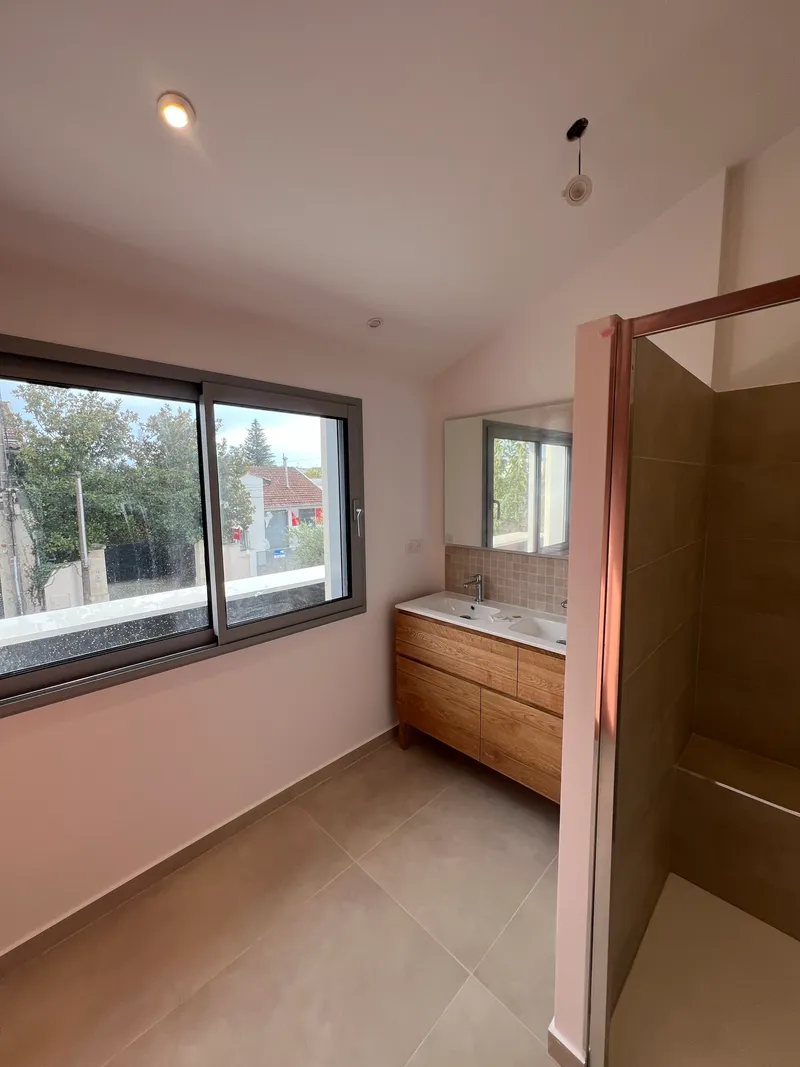Salle de bains moderne avec meuble vasque en bois et grande fenêtre