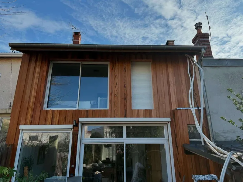 Façade de maison habillée de bardage en bois avec de grandes baies vitrées